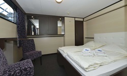 Die Juniorsuite mit großem Doppelbett, zwei Sesseln und einem Fenster auf dem Hauptdeck der MS Serena