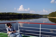 Eine Frau auf dem Sonnendeck der MS Classic Lady genießt die umwerfende Landschaft in Masuren