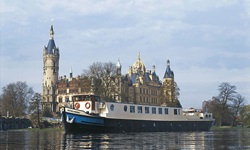 Die MS Mecklenburg auf dem Wasser. Im Hintergrund ein großes Schloss