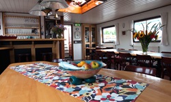 Ein Tisch mit einer Obstschale im Salon der MS Sarah. Im Hintergrund befindet sich die Bar.