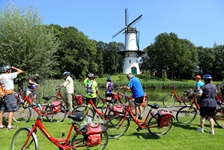 Eine Radlergruppe betrachtet eine Mühle beim niederländischen Tholen.