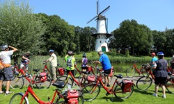 Eine Radlergruppe betrachtet eine Mühle beim niederländischen Tholen.