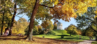 Blick auf den von herbstlich gefärbten Bäumen umrahmten Monopteros im Englischen Garten von München.