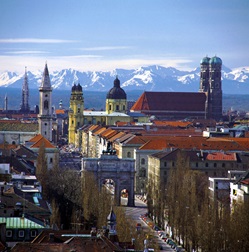 Blick über die bayerische Landeshauptstadt München mit ihren zahlreichen Kirchen, deren Türme weit in die Höhe ragen - dahinter die einzigartige Alpenkulisse