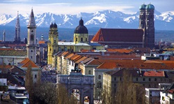 Blick über die bayerische Landeshauptstadt München mit ihren zahlreichen Kirchen, deren Türme weit in die Höhe ragen - dahinter die einzigartige Alpenkulisse