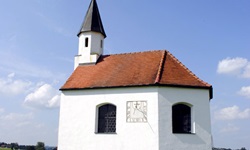 Eine Kapelle mit Sonnenuhr auf einer Wiese