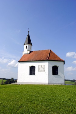 Eine Kapelle mit Sonnenuhr auf einer Wiese