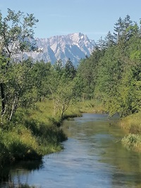 Blick über einen Fluss bis hin zu den Alpen bei der Münchner Seenrunde