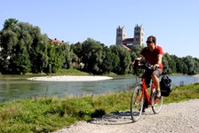 Ein Radfahrer fährt auf einem schottrigen Radweg der Isar entlang