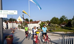 Drei Radfahrer radeln auf einer Brücke über die Isar