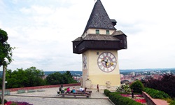 Eine Gruppe macht beim Uhrturm in Graz Pause und genießt den herrlichen Ausblick auf die Stadt.