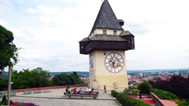 Eine Gruppe macht beim Uhrturm in Graz Pause und genießt den herrlichen Ausblick auf die Stadt.