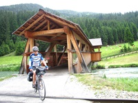 Ein Radler beim Verlassen einer überdachten Holzbrücke über die Mur.