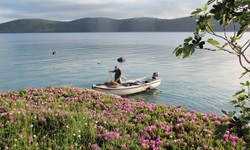 Ein Fischer auf seinem Boot hantiert mit seinem Fischernetz im Meer von Dalmatien