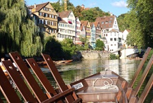 Blick von einem Stocherkanu auf dem Neckar zu einer Häuserreihe an der Promenade