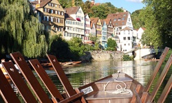 Blick von einem Stocherkanu auf dem Neckar zu einer Häuserreihe an der Promenade