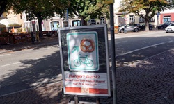 Blick auf ein Schild, das den Neckar-Radweg mit einer Brezel zeigt und an einer Bäckerei vorbei führt