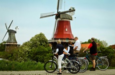 Eine Radlergruppe macht Pause und bestaunt die Windmühlen von Greetsiel.