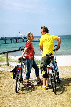 Zwei Radfahrer stehen am Strand der Ostsee neben ihren Rädern