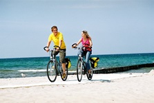 Zwei Radfahrer fahren auf einem Deich an der Ostsee entlang