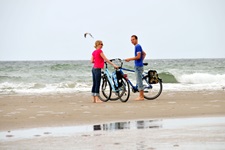 Zwei Radfahrer stehen am Strand der Ostsee neben ihren Rädern