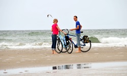 Zwei Radfahrer stehen am Strand der Ostsee neben ihren Rädern