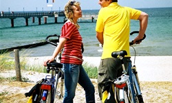 Zwei Radfahrer stehen neben ihren Rädern am Strand der Ostsee