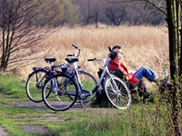 Zwei Radfahrer sitzen auf einer Bank und machen eine Pause - hinter sich sind ihre Räder abgestellt