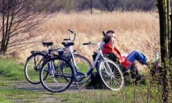 Zwei Radfahrer sitzen auf einer Bank und machen eine Pause - hinter sich sind ihre Räder abgestellt