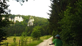 Eine Radfahrerin auf dem schottrigen Donau-Radweg im beeindruckenden Donautal mit seinen schroffen und teilweise bewachsenen Felsen