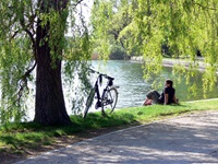 Ein Radfahrer sitzt auf einer Wiese eines Sees an der Müritzer Seenplatte - neben sich hat er sein Rad abgestellt