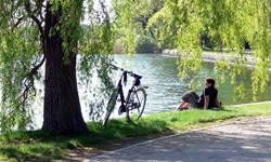 Ein Radfahrer sitzt auf einer Wiese eines Sees an der Müritzer Seenplatte - neben sich hat er sein Rad abgestellt