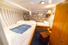 Eine Drei-Bett-Kabine mit einem französischen Bett und einem Einzelbett auf der Panagiota. Auf dem französischem Bett liegen blaue Handtücher