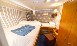 Eine Drei-Bett-Kabine mit einem französischen Bett und einem Einzelbett auf der Panagiota. Auf dem französischem Bett liegen blaue Handtücher