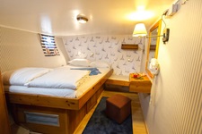 Eine Doppelkabine mit erhöhtem französischem Bett, Spiegel und braunem Hocken