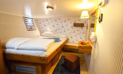 Eine Doppelkabine mit erhöhtem französischem Bett, Spiegel und braunem Hocken