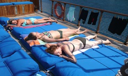 Drei junge Frauen im Bikini lassen sich auf den blauen Liegematten auf dem Sonnendeck der Panagiota von der Sonne braten.