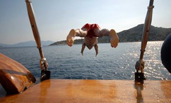 Ein junger Mann in roter Badehose verlässt die Panagiota mit einem Kopfsprung ins Meer.