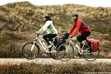 Zwei Radfahrer radeln auf einem Weg durch Dänemarks Dünen