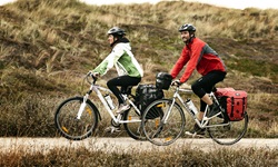 Zwei Radfahrer radeln auf einem Weg durch Dänemarks Dünen