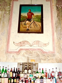 Ein Flaschen-Stilleben vor einer Hauswand mit "Radlergemälde".