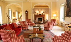 Blick in einen Aufenthaltsraum mit offenen Kamin und rot-beige gestreiften Ohrensesseln des Hotels Sina Villa Matilde