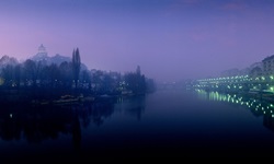 Blick über den Fluss Po bei Nacht, der durch das beleuchtete Turin fließt
