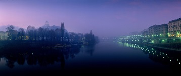 Blick über den Fluss Po bei Nacht, der durch das beleuchtete Turin fließt