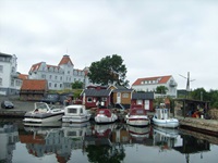 Blick auf einen kleinen Hafen mit angelegten Booten und Bootshäusern an der dänischen Insel Bornholm