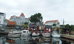 Blick auf einen kleinen Hafen mit angelegten Booten und Bootshäusern an der dänischen Insel Bornholm