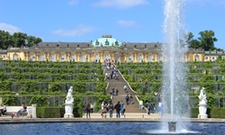Touristen bummeln durch die terrassenförmig angelegten Gärten von Schloss Sanssouci.