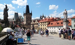 Touristen flanieren auf der für ihre Statuen berühmten Karlsbrücke in Prag, im Hintergrund die Prager Altstadt.