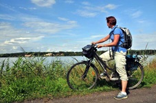 Eine Radlerin steht am Rand der Rhone und blickt in die Landschaft