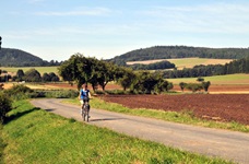 Eine Radlerin fährt auf einem asphaltierten Weg entlang